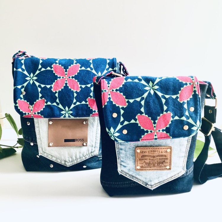 Two bright pink and blue floral messenger bags sitting side by side on a white surface